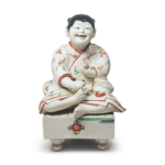 Figure of a boy seated on go-game board, enamelled ware