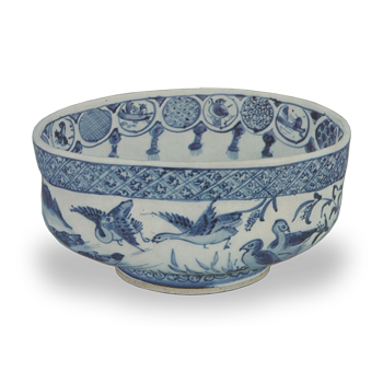 Attachment Box, chamfering, calligraphy, gold powder lettering Attributed to the Fujita family Dimensions Height: 5.9-6.3cm, Bowl diameter: 9.9-12.6cm, Base diameter: 6.4cm, Height: 1.0cm, Weight: 270 　This is a truly fresh bowl. It is a tea bowl that is a model of what Shozui should be. As the name “Kutsu-shape” suggests, the body of the bowl is slightly extended into an oval shape, and the lower part of the decorative design on the rim of the bowl is lightly pressed inward to form a Kutsu-chawan shape. The wide rim and low center of gravity are balanced by the large base. 　The outer surface of the bowl has a cobblestone pattern around the mouth rim and a cylindrical arabesque pattern around the base. The upper and lower parts of the bowl are covered with a band of cobblestone patterns, and around the base of the bowl is a cylindrical arabesque design. Looking at the body of the goose, the wings are painted in dark underglaze blue, and the body is painted in light underglaze blue, creating fine differences in nuance. This method of painting in underglaze blue is related to the Yasukuma underglaze blue that was to follow. The inner surface is lined with circles around the rim, each circle is decorated with a landscape, such as Ashiba Daruma and Higashi Hantoukisou, as well as fine ground patterns such as cobblestones and diagonal latticework. The wink and wink lines hanging down between the circles are also in the usual pattern.