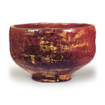 Amayū Tea Bowl, Inscribed “Kan-kiku,” by Dōnyū Height: 8.8 cm, Mouth Diameter: 12.5 cm, Foot Diameter: 6.0 cm This is likely one of Dōnyū’s earliest red raku tea bowls, and its form appears to be based on the Chōjirō-yaki style. The rim curves slightly inward, the body is slender and taut, and the lower section is rounded yet slightly raised. The foot is sharply carved, with a flat footring, and the character “Raku” is clearly stamped inside the foot. Yellow earthenware clay was applied with a brush over the raw clay body, and glaze was applied over that, resulting in a glaze color that shifts like amber glaze. Furthermore, some areas from the rim to the body show fire-induced color changes, and brushstrokes appear in yellow in certain sections. This is one of the representative works among Michiiri’s red raku tea bowls. On the underside of the inner box lid, Ittō has inscribed “Nonkou Red Tea Bowl, Kan-kiku (seal mark),” and on the outer box, Fuzan Seikō has inscribed “Nonkou Red Tea Bowl, also inscribed by Gensai, Kan-kiku (seal mark).”